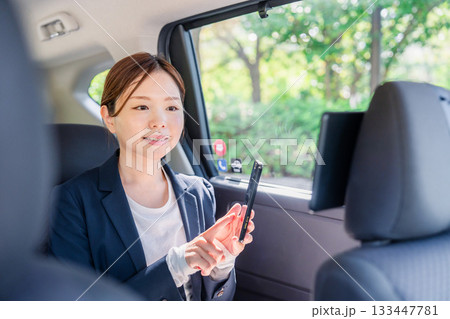 タクシーでスマホを使う若い女性ビジネスパーソン 133447781