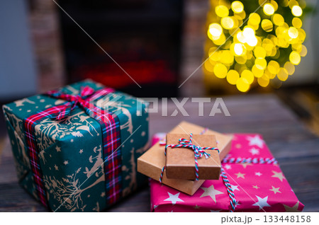 Cozy Christmas Interior with Fireplace, Gift Boxes, and Decorated Tree with Warm Lights Cozy Christmas Interior with Fireplace, Gift Boxes, and Decorated Tree with Warm Lights 133448158