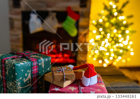 Cozy Christmas Interior with Fireplace, Gift Boxes, and Decorated Tree with Warm Lights 133448161