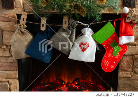 Advent Calendar Bags and Christmas Stockings Hanging Above Cozy Fireplace Advent Calendar Bags and Christmas Stockings Hanging Above Cozy Fireplace 133448227