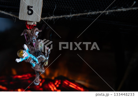Krampus Ornament Carrying Child Hanging on Advent Garland Above Fireplace 133448233