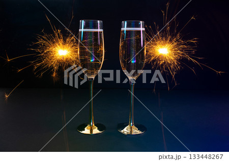 Happy New Year 2026, New Year's Eve holiday greeting card celebration. Sparklers firework, champagne glasses on black background 133448267