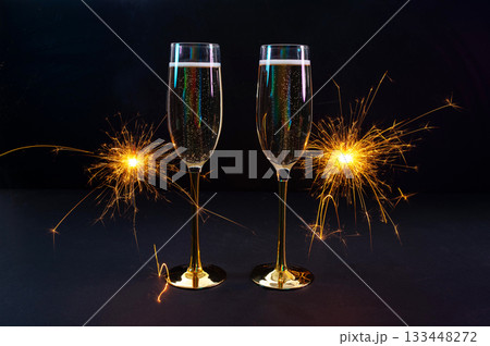 Happy New Year 2026, New Year's Eve holiday greeting card celebration. Sparklers firework, champagne glasses on black background 133448272
