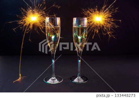 Happy New Year 2026, New Year's Eve holiday greeting card celebration. Sparklers firework, champagne glasses on black background 133448273