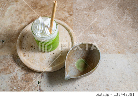 Matcha latte glass, matcha bowl, a bamboo whisk Chasen on travertine tray 133448381