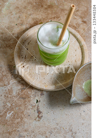 Matcha latte glass, matcha bowl, a bamboo whisk Chasen on travertine tray 133448384