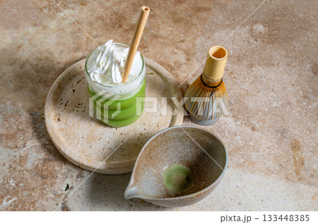Matcha latte glass, matcha bowl, a bamboo whisk Chasen on travertine tray 133448385