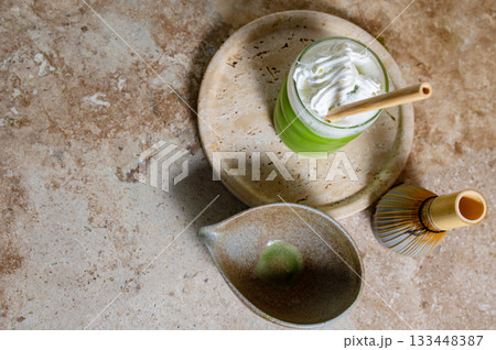 Matcha latte glass, matcha bowl, a bamboo whisk Chasen on travertine tray 133448387