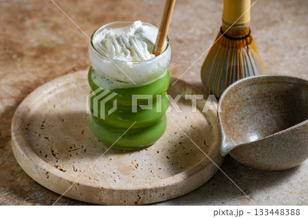 Matcha latte glass, matcha bowl, a bamboo whisk Chasen on travertine tray 133448388