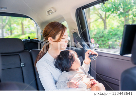 タクシーでシートベルトをする子連れのお母さん 133448641