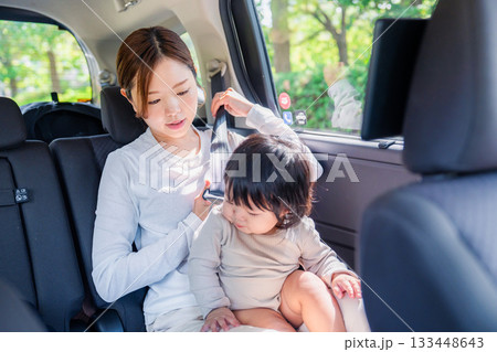 タクシーでシートベルトをする子連れのお母さん 133448643