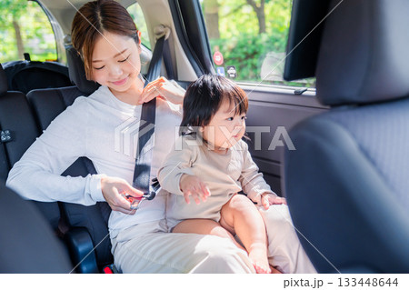 タクシーでシートベルトをする子連れのお母さん 133448644