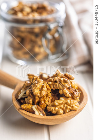 Peeled walnut kernels on wooden spoon on white table. 133448715