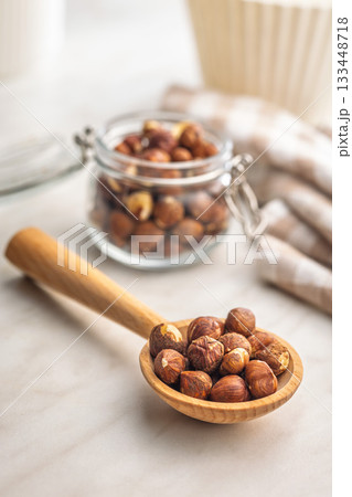 Peeled hazelnut kernels on wooden spoon on kitchen table. Peeled hazelnut kernels on wooden spoon on kitchen table. 133448718