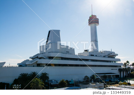 真っ青な青空とまぶしい日差しの下の白壁とオレンジ色の展望台の船の科学館の建物 133449359