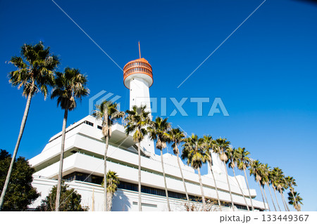 真っ青な青空とまぶしい日差しの下の白壁とオレンジ色の展望台の船の科学館の建物 133449367