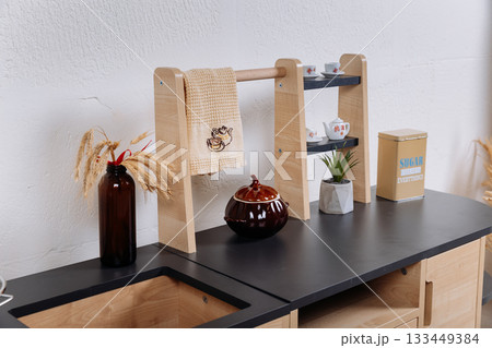 Close up of wooden toy kitchen countertop with towel rack and miniature tea set 133449384