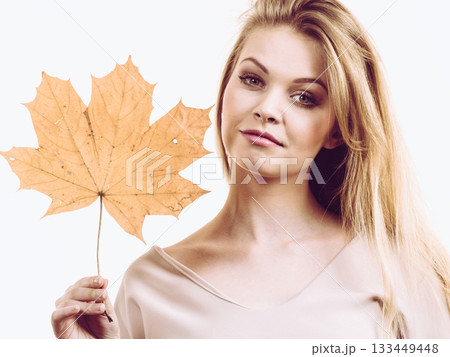Woman holding maple leaf in hand Woman holding maple leaf in hand 133449448
