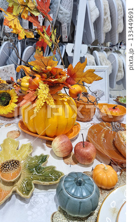 Autumn-themed decorative table display featuring pumpkins, leaves, and seasonal fruits Autumn-themed decorative table display featuring pumpkins, leaves, and seasonal fruits 133449691