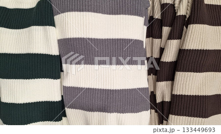 Top view of folded striped and solid knit sweaters 133449693