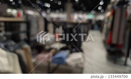 Blurred indoor market scene showcasing a variety of clothing and textile stalls under bright lights 133449700