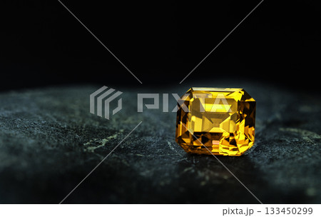 A yellow gemstone sits on a dark surface A yellow gemstone sits on a dark surface 133450299