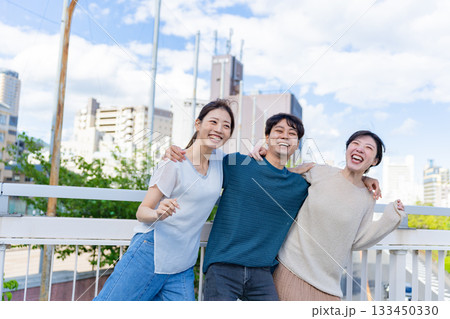 街中で肩を組んで笑う3人の友人たちの爽やかなスナップ 133450330