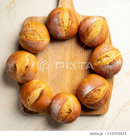 Freshly baked round bread rolls arranged in a circle on a wooden board, showcasing their golden crust and soft texture Freshly baked round bread rolls arranged in a circle on a wooden board, showcasing their golden crust and soft texture 133450835