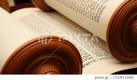 A close-up view of an open Torah scroll, revealing ancient Hebrew script on parchment. This image conveys a sense of sacred tradition, history, and faith. Perfect for religious content. 133451040