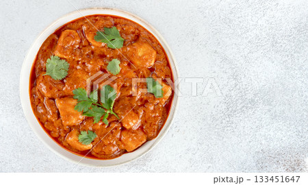 Indian butter chicken curry in a white bowl with fresh cilantro on white background. Top view. Copy space. Banner Indian butter chicken curry in a white bowl with fresh cilantro on white background. Top view. Copy space. Banner 133451647