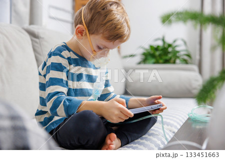 Child Using Nebulizer While Playing on Tablet at Home Child Using Nebulizer While Playing on Tablet at Home 133451663