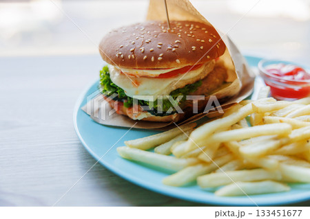 Delicious Cheeseburger with Fries on a Blue Plate Delicious Cheeseburger with Fries on a Blue Plate 133451677