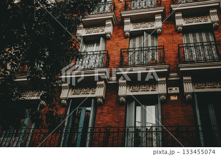 Historic building facade with balconies and brickwork. A close-up shot of a beautiful brick building in an European city, featuring balconies, ornate details, and architectural design. Historic building facade with balconies and brickwork. A close-up shot of a beautiful brick building in an European city, featuring balconies, ornate details, and architectural design. 133455074