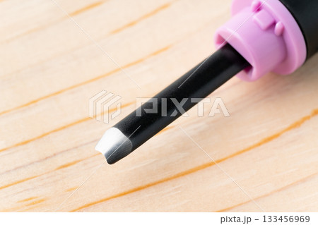 木板と彫刻刀の丸刀（小丸刀）の刃先の裏側のクローズアップ 133456969