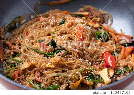 Japchae, Korean stir fried glass noodles with vegetables, pork, soy sauce and sesame oil  133457165