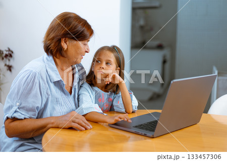 Grandmother and granddaughter using laptop 133457306