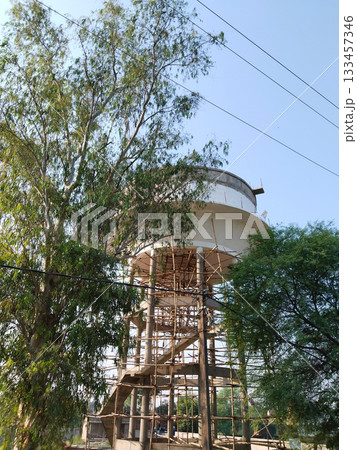 making a new water supply tank in a village of india. construction site of water tank. New white water tank, water pipes underneath for support water. making a new water supply tank in a village of india. construction site of water tank. New white water tank, water pipes underneath for support water. 133457346