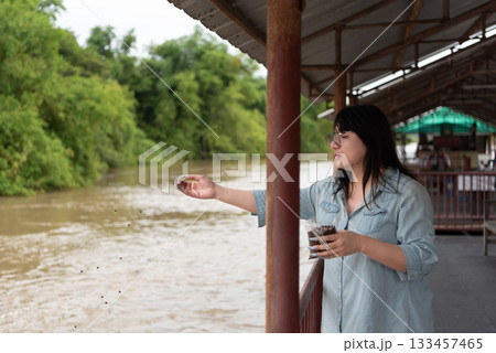 Two LGBTQ close friends, feeding fish in the alms zone by the river at a Thai temple. The activity symbolizes compassion and giving, a serene and peaceful moment by the water. Two LGBTQ close friends, feeding fish in the alms zone by the river at a Thai temple. The activity symbolizes compassion and giving, a serene and peaceful moment by the water. 133457465