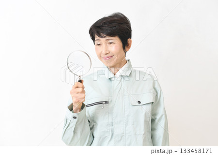 虫眼鏡を持つ作業服姿のアジア人のミドル女性 133458171