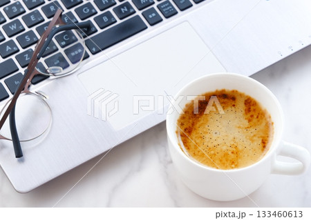 パソコンとコーヒー - 淹れたてのコーヒーを飲みながら、ノートパソコンでデスクワーク中のイメージ パソコンとコーヒー - 淹れたてのコーヒーを飲みながら、ノートパソコンでデスクワーク中のイメージ 133460613