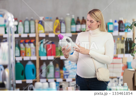 Interested pregnant woman choosing safe laundry detergent in store 133461854