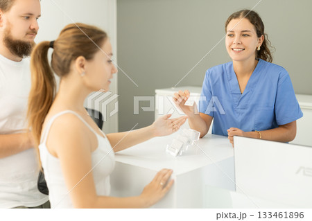 Woman stands near the reception and communicates with the administrator of the clinic 133461896
