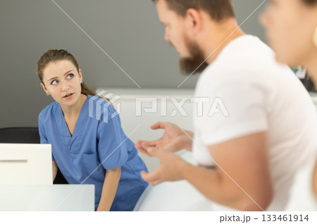 Man stands near the reception and asks questions to the administrator in the dentistry Man stands near the reception and asks questions to the administrator in the dentistry 133461914