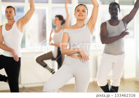 Young Asian woman practicing basic ballet movements at group class Young Asian woman practicing basic ballet movements at group class 133462316