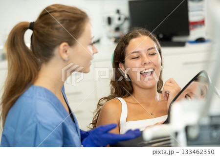 Woman at dentist appointment looking in mirror Woman at dentist appointment looking in mirror 133462350
