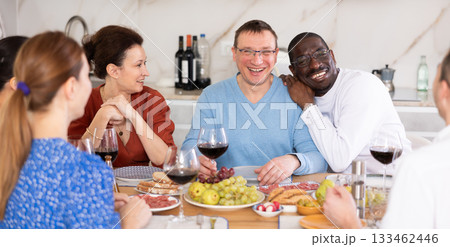 Companions congregated around a festive table, participating in animated discussions and enjoying the delights of red wine 133462446