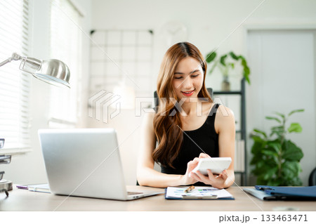 Asian woman using calculator while working on laptop at home office, concept of finance, business planning, productivity, and success. Asian woman using calculator while working on laptop at home office, concept of finance, business planning, productivity, and success. 133463471