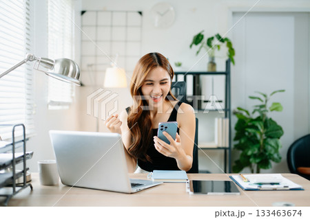 Cheerful businesswoman celebrating success at work, raising fists in joy at laptop, symbolizing achievement, motivation 133463674