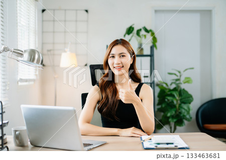Smiling businesswoman showing thumbs up in bright modern office, symbolizing success, approval, and confidence in professional achievement. Smiling businesswoman showing thumbs up in bright modern office, symbolizing success, approval, and confidence in professional achievement. 133463681