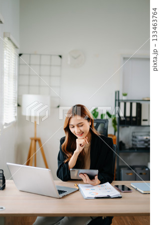 Business woman using tablet and laptop for doing math finance on an office desk, tax, report, accounting, statistics, and analytical research concept in office 133463764